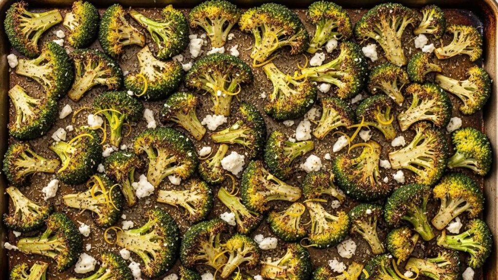 Crispy roasted broccoli on a sheet pan topped with lemon zest, feta and herbs.