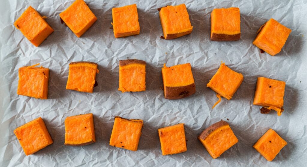 Close up of oven roasted sweet potato cubes spaced out for maximum crispiness.