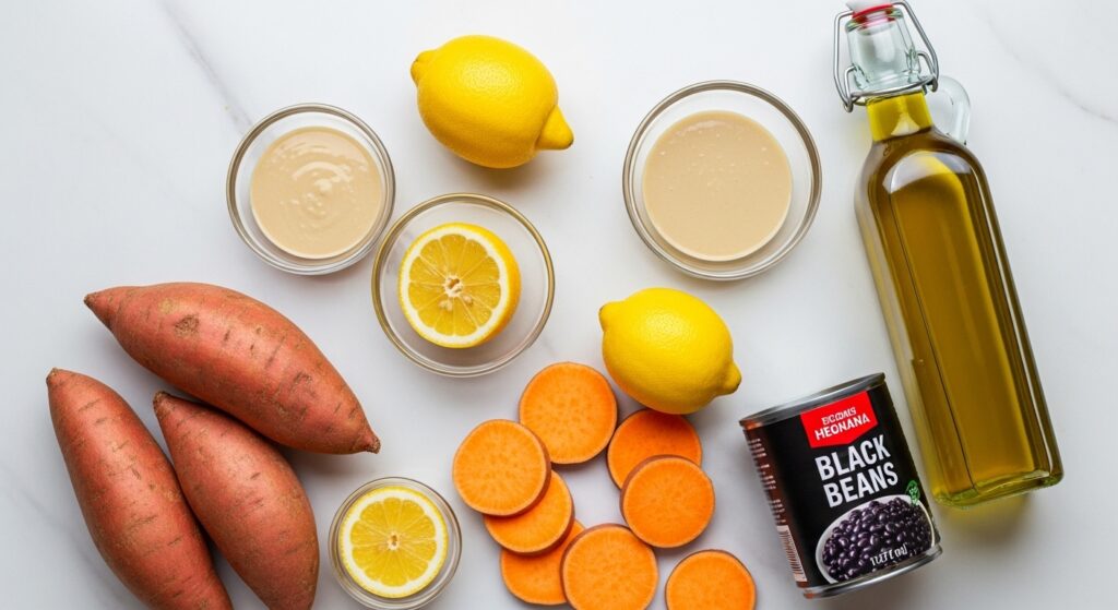 Fresh ingredients for a roasted sweet potato bowl recipe including black beans, quinoa, tahini, and vegetables.
