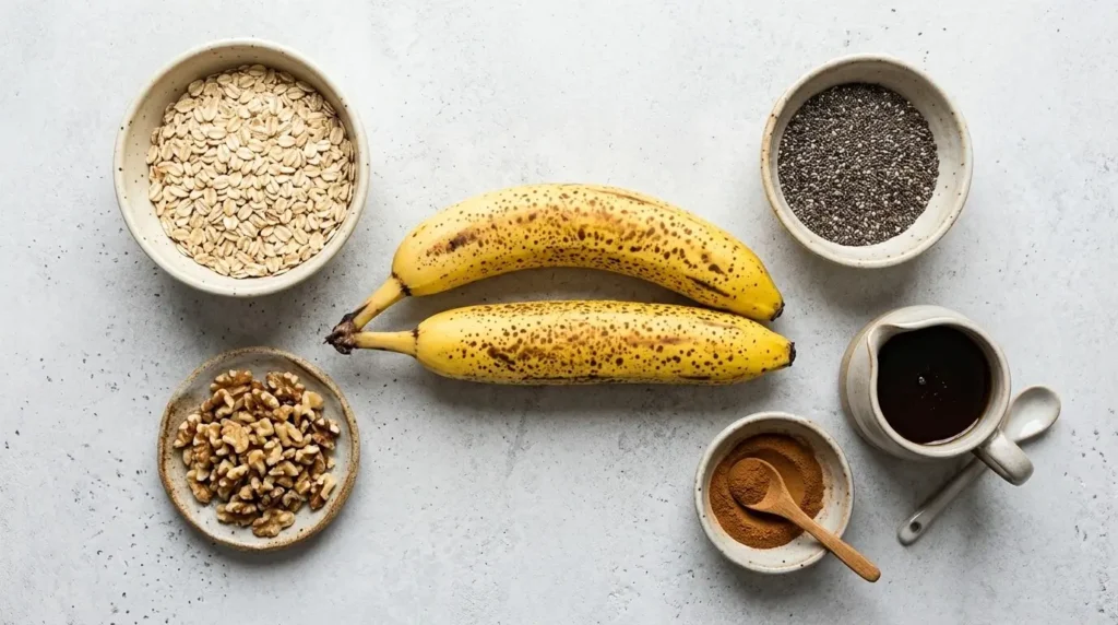 Ingredient flat lay showing ripe bananas, rolled oats, chia seeds, maple syrup, and cinnamon.