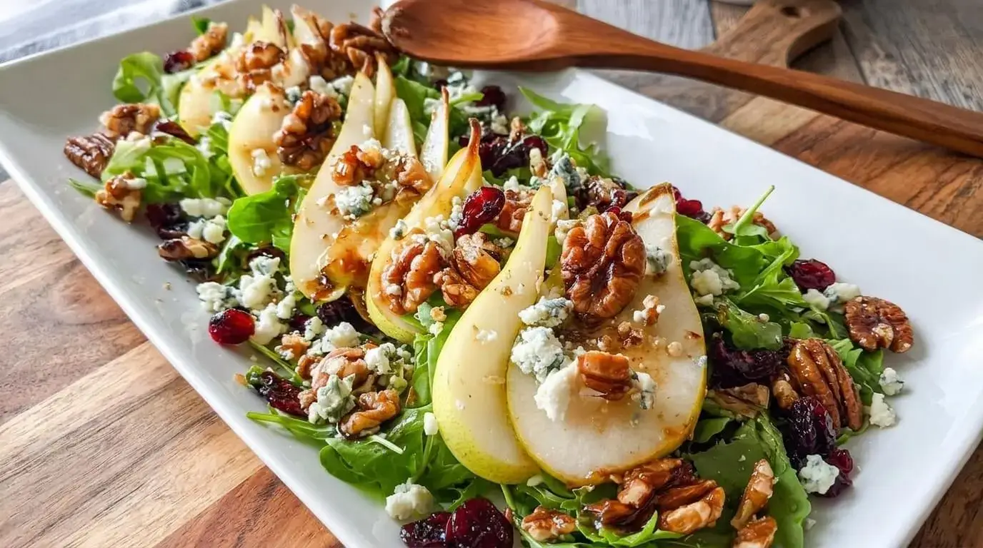 Pear, Gorgonzola and Candied Pecan Salad served on a long white platter over a rustic wooden table.