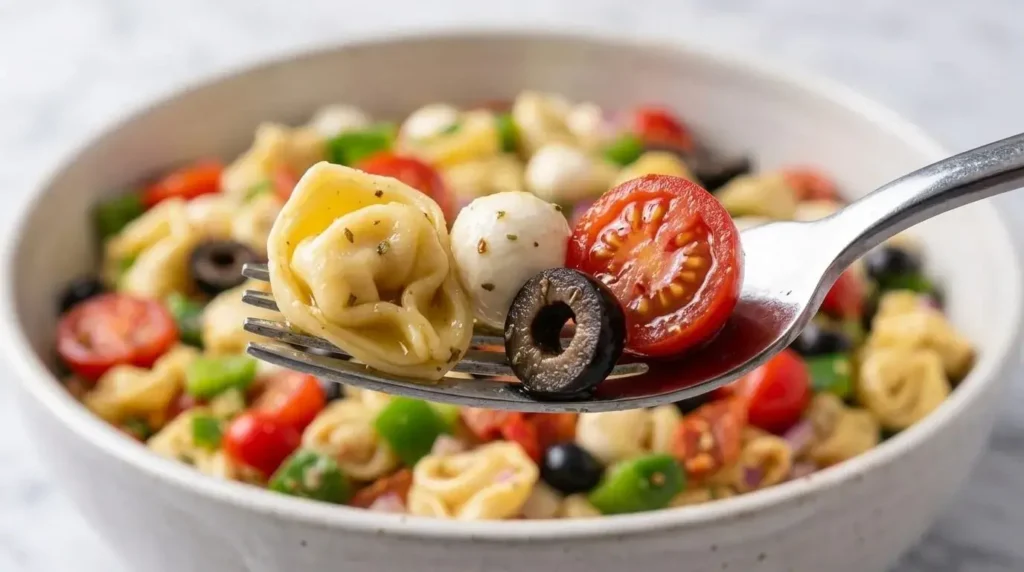 Close up of cheese tortellini, fresh mozzarella pearl, and cherry tomato on a fork