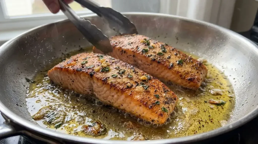 Searing salmon fillets in a skillet with olive oil for creamy seafood recipe.